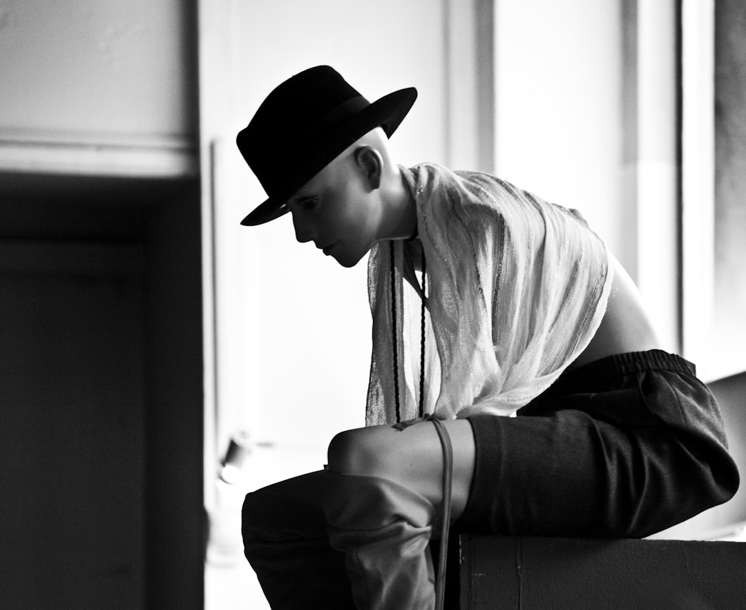 A man sitting on a suitcase with a hat on