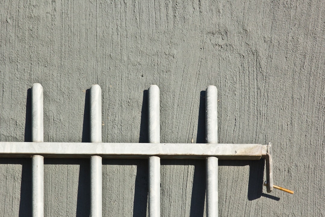 A bird perched on top of a white fence