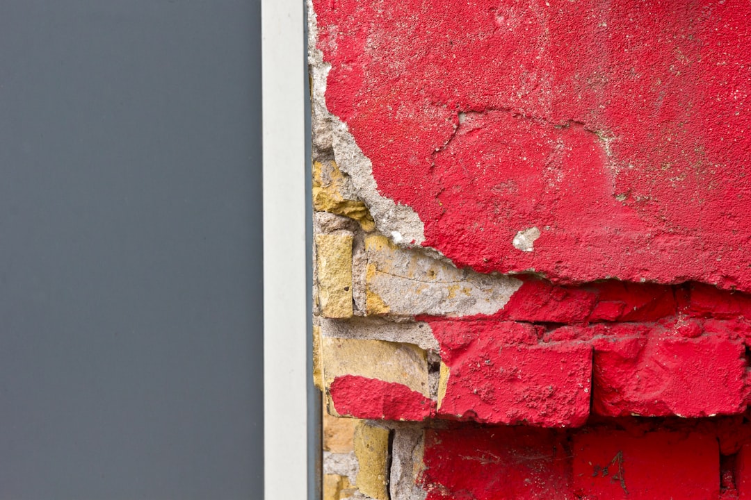 A red and yellow fire hydrant sitting next to a red brick wall