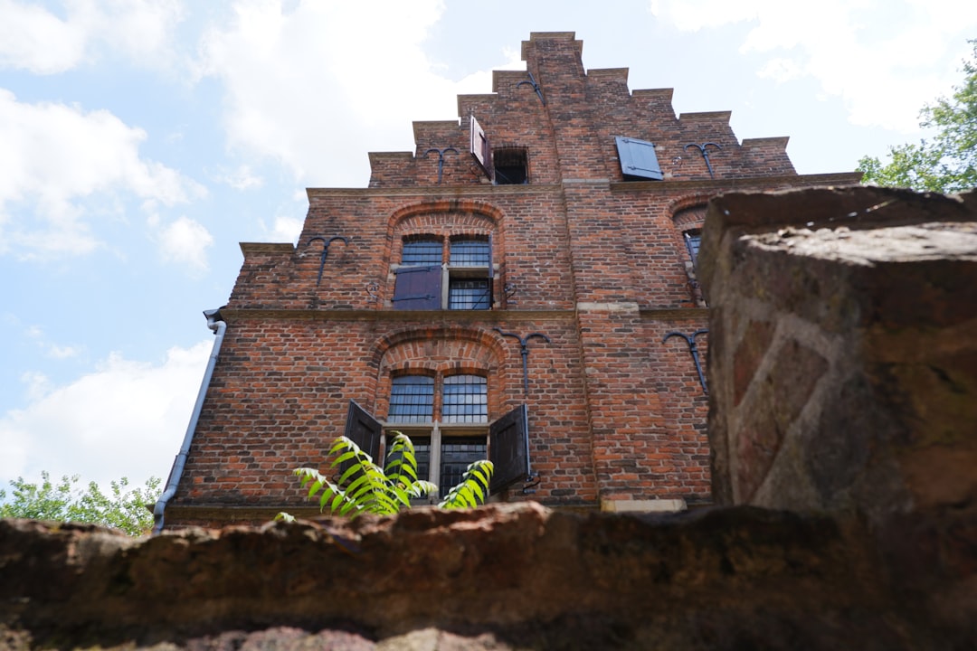 a tall brick building with a green plant in front of it